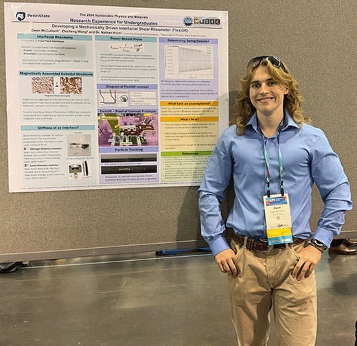 Owen McCulloch standing in front of his research poster